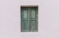 Old fashioned worn window with green wooden shutters, closed, on painted wall background