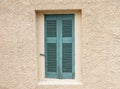 Old fashioned worn window with green wooden shutters, closed, on plastered wall background Royalty Free Stock Photo