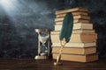 Old feather quill ink pen with inkwell and old books over wooden desk in front of black wall background. Conceptual photo on Royalty Free Stock Photo