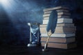 Old feather quill ink pen with inkwell and old books over wooden desk in front of black wall background. Conceptual photo on Royalty Free Stock Photo