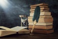 Old feather quill ink pen with inkwell and old books over wooden desk in front of black wall background. Conceptual photo on Royalty Free Stock Photo