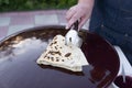 Old female chef, cook holding wrapped taco, pita, cooking, frying on frying pan outdoor. Royalty Free Stock Photo