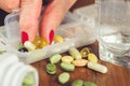 Old female fingers with manicure take omega 3 capsule from the container with mix of vitamins and supplements. Royalty Free Stock Photo