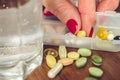 Old female fingers with manicure take the pill from the container with mix of vitamins and supplements. Royalty Free Stock Photo