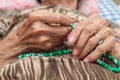 Old female hands holding green praying beads Royalty Free Stock Photo