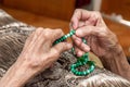 Old female hands holding green praying beads Royalty Free Stock Photo