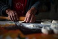 Old female hands at work in the kitchen. Grandmother rolls out a piece of dough with rolling pin. Cooking process Royalty Free Stock Photo