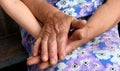 Old female wrinkled hands hold baby hand between to protect