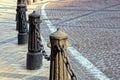 Iron old pillars with chain on the sidewalk near the road Royalty Free Stock Photo