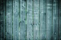 Old fence of boards with faded paint. Empty dark turquoise background, with vignette. Texture of wooden slats.