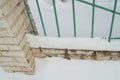 Old fence with metal bars and brick posts, cracked plaster due to adverse weather conditions, outdoors, snow, winter, cold