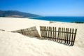 Old fence sticking out of deserted sandy beach dunes Royalty Free Stock Photo