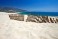 Old fence sticking out of deserted sandy beach dunes Royalty Free Stock Photo