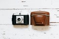 Old film camera in brown vintage case and a roll of film on wood background. top view, text space Royalty Free Stock Photo