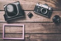 Old film camera with lens, case, photo frame and film on wooden background. Vintage toned and top view Royalty Free Stock Photo