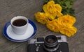 The old film camera, roses and coffee on a wooden table