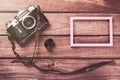 Old film camera with strap, photo frame and film on wooden background. Vintage toned and top view Royalty Free Stock Photo