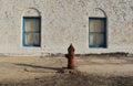 Old fire hydrant on the background of a white wall and blue windows Royalty Free Stock Photo