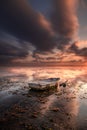 Old fisherman boat. Seascape. Fishing boat at the beach during sunrise. Low tide. Water reflection. Cloudy sky. Slow shutter speed