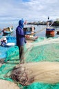 An old fisherman is removing anchovies fish from his fishing net to begin a new working day in Ly Son island Royalty Free Stock Photo