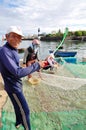 An old fisherman is removing anchovies fish from his fishing net to begin a new working day in Ly Son island Royalty Free Stock Photo