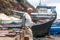 An old fisherman repairs his boat on the ocean Royalty Free Stock Photo