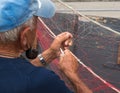 Senior fisherman repairs fishing net