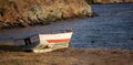 Old fishing boat abandoned on the sand. Blur rocks and sea background Royalty Free Stock Photo