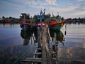 Old fishing boat near wooden jetty. Beautiful malaysian landscape. Sunset reflection in the water. Royalty Free Stock Photo