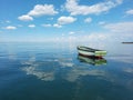 An old fishing boat off the coast of the sea. An empty little wooden boat on a calm sea surface. Royalty Free Stock Photo
