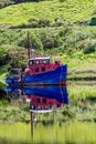 Old fishing boat reflecting in the water, anchored in Clifden Bay at high tide