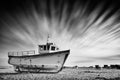 Old fishing boat stranded on a pebbled beach with dramatic long-exposure sky. Dungeness, England Royalty Free Stock Photo