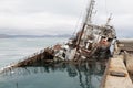 An old fishing boat sunk at a pier in seaport Royalty Free Stock Photo