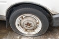 Old flat wheel of a white car with a rusty tire. Close Up old fl Royalty Free Stock Photo