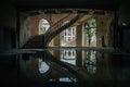 Old flooded abandoned mansion with spiral stair, water reflection