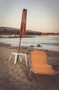 Old folding beach lounge and a wooden umbrella frame on a sandy shore