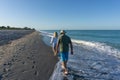 Old folks walk down beach near Tampa, Florida