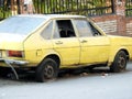 old forgotten retro rusty dirty yellow car parked in the street with damaged tires, dusty broken car, rusty wreck