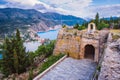 Old fort gate on top of frourio peninsular and Assos village with beautiful sea bay and cypress trees in background