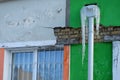 Old foundation and plaster wall with cracks. Building requiring repair closeup. Frozen rain gutter with Icicles. Royalty Free Stock Photo