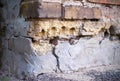 Old foundation and plaster wall with cracks. Building requiring repair closeup Royalty Free Stock Photo