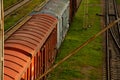 Old freight cars of the train stand on rails. The train stopped at the station in the village. Rusty iron cars and green grass.