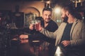 Old friends drinking draft beer at bar counter in pub.