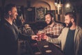 Old friends drinking draft beer at bar counter in pub.