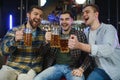 Old friends meeting. Happy young men in casual wear toasting with beer while sitting in beer pub together Royalty Free Stock Photo