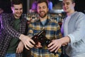 Old friends meeting. Happy young men in casual wear toasting with beer while sitting in beer pub together Royalty Free Stock Photo