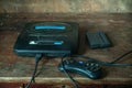 An old game console with a cartridge and a joystick from the 90s, in the dust on a wooden table in the dust Royalty Free Stock Photo