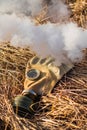 Old gas mask in smoke on the ground isolated.