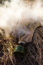 Old gas mask in smoke on the ground isolated