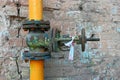 Old gas pipe painted in yellow pipe and rusty valve with spots of obsolete paint at brick wall Royalty Free Stock Photo